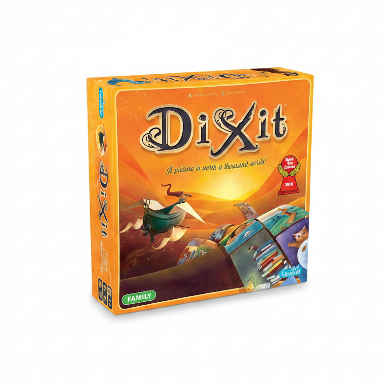 The board game box for 'Dixit' is shown at a three-quarter angle. The packaging features a vibrant orange and yellow desert sunset illustration with a flying bird and a tilted road of books.