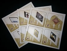 A set of five illustrated cards or inserts fanned out on a black background. Each card has a beige and gold border with small printed images and text, including a circular emblem and a portrait.
