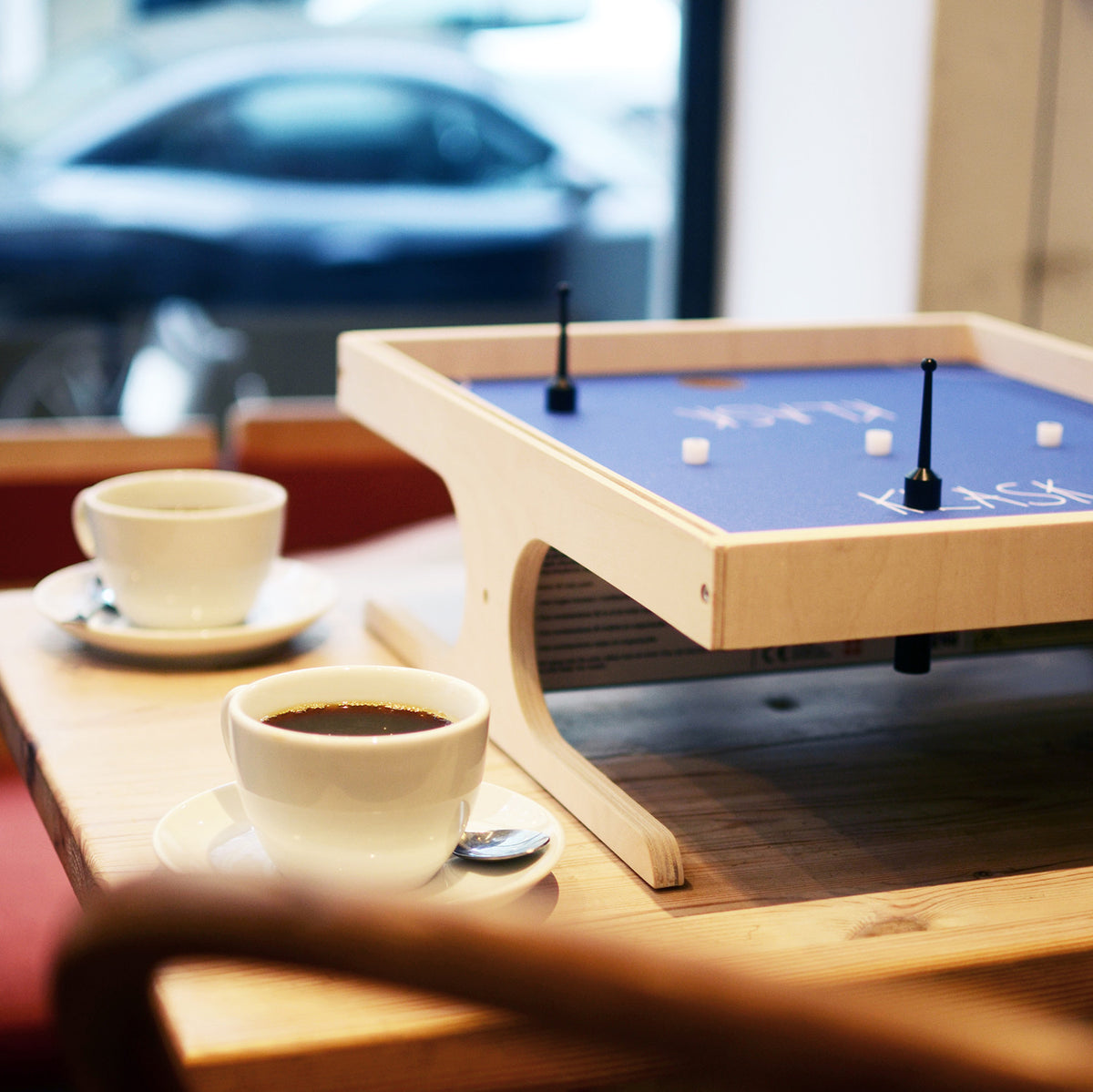 Card game setup on a small table with cups of coffee in a casual setting.